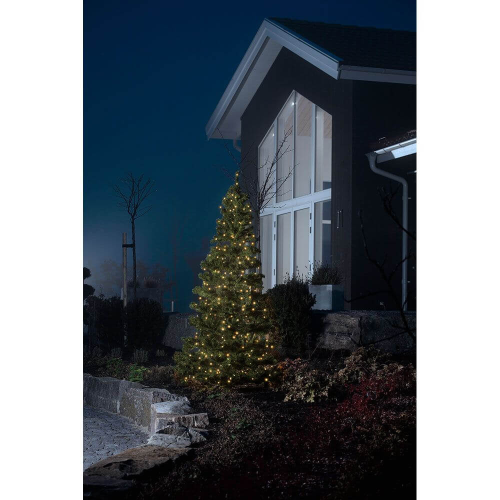 Micro LED System Erweiterung Lichterkette 100 Dioden Berstein IP44 erleuchtet einen Baum vor einem modernen Haus.