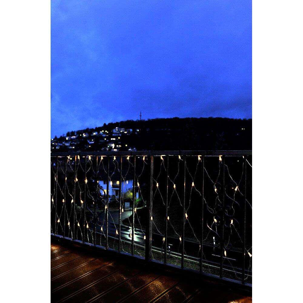 Microlight Lichternetz 160 klare Birnen IP44 an einem Balkon bei Nacht mit warmer Beleuchtung.