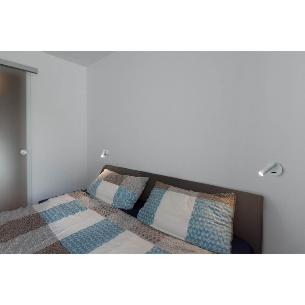 Milan Single Spot LED Wandspot 3000K Weiß über dem Bett in modernem Schlafzimmer mit weißen und blauen Akzenten.