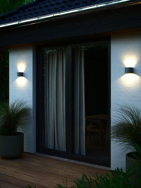Applique murale Milda LED IP44 crée un effet lumineux intéressant sur le mur et éclaire l’entrée.