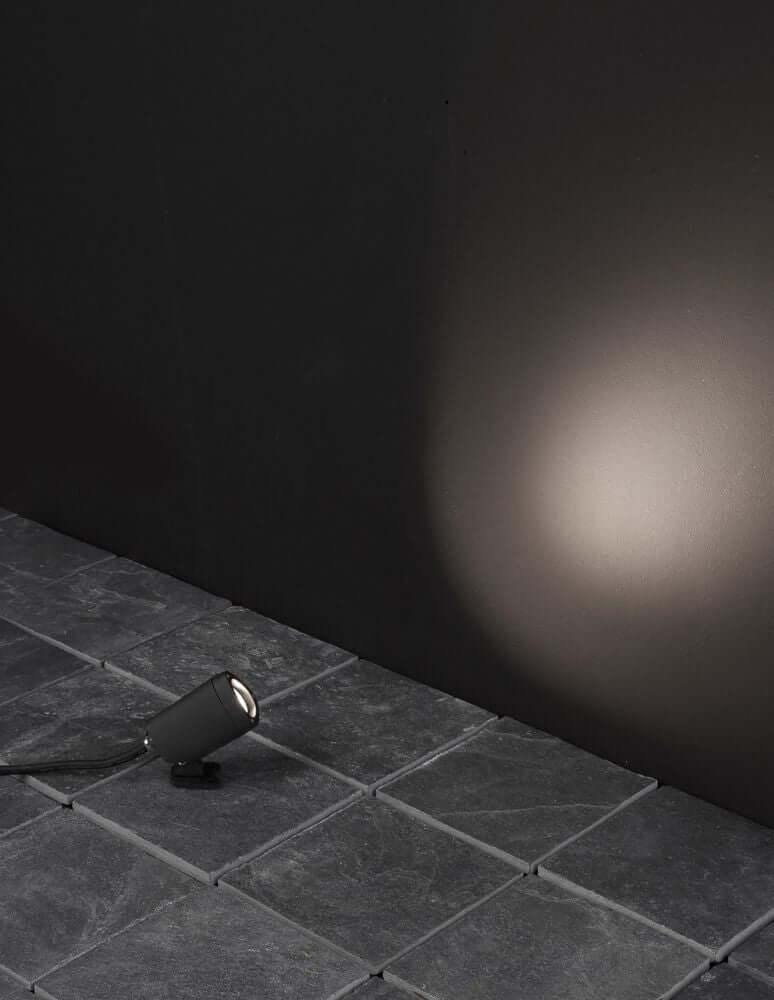 Mini LED Außenwandleuchte 3000K Schwarz IP65 auf einem Steinboden mit warmem Licht an der Wand.