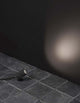 Mini LED Außenwandleuchte 3000K Schwarz IP65 auf einem Steinboden mit warmem Licht an der Wand.