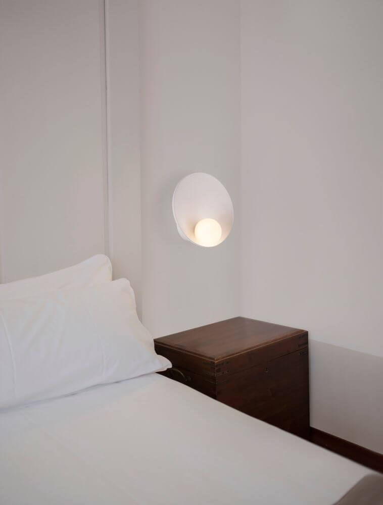 Minim Wandleuchte G9 an einer Wand neben einem Bett in einem modernen Schlafzimmer.