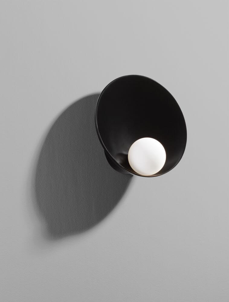 Minim Wandleuchte G9 in schwarzem Design mit runder Lichtquelle an grauer Wand.