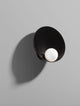 Minim Wandleuchte G9 in schwarzem Design mit runder Lichtquelle an grauer Wand.