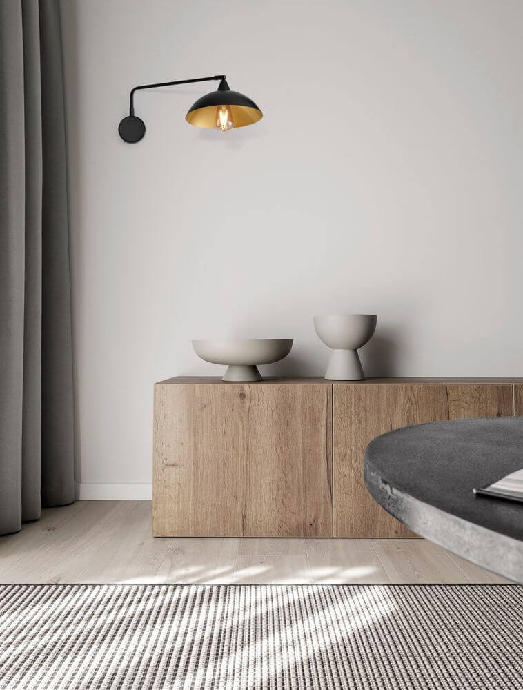 Mirba Wandleuchte Schwarz, Gold über einem modernen Sideboard in einem stilvollen Raum.
