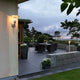 Mode Außen-Wandleuchte galvanisierter Stahl, klares Polycarbonat Glas an einer Terrasse bei Abenddämmerung.