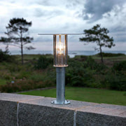 Mode bollard light galvanized steel, clear polycarbonate glass on a garden wall overlooking the landscape.