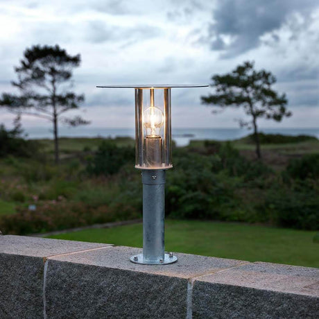 Mode bollard light galvanized steel, clear polycarbonate glass on a garden wall overlooking the landscape.
