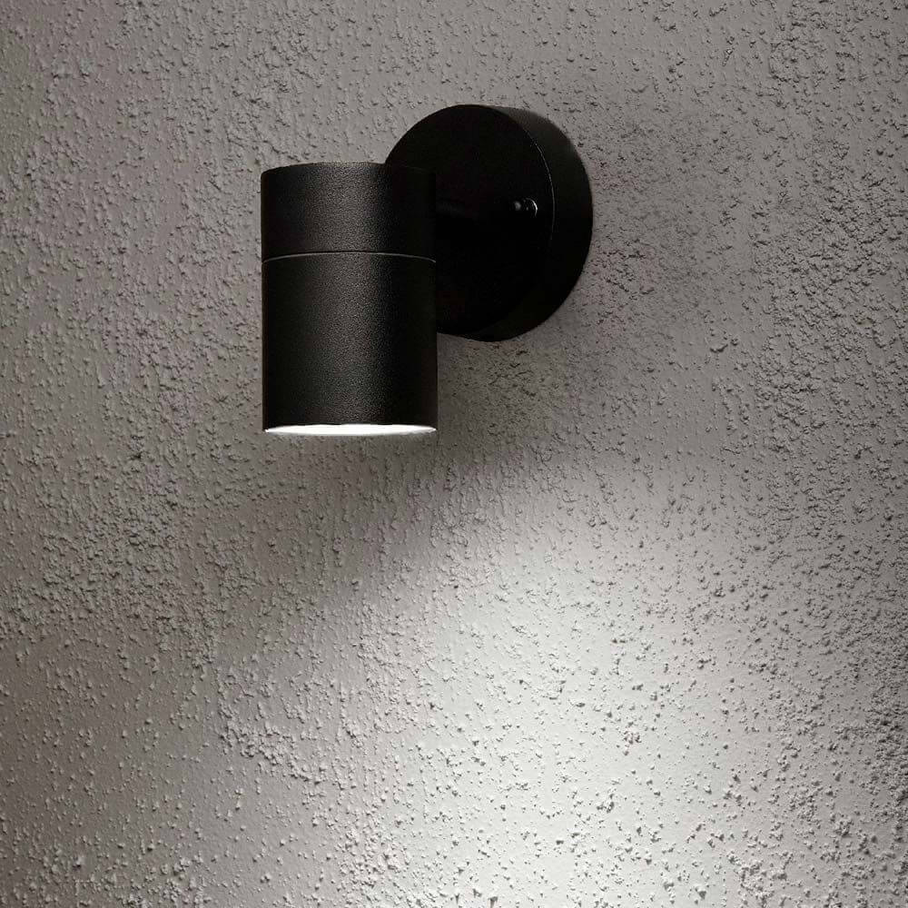 Modena Außen-Wandleuchte Schwarz, klares Glas, Reflektor an einer strukturierten Wand montiert.