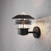 Modena udendørs væglampe sort, klart glas monteret på en væg med et moderne design.