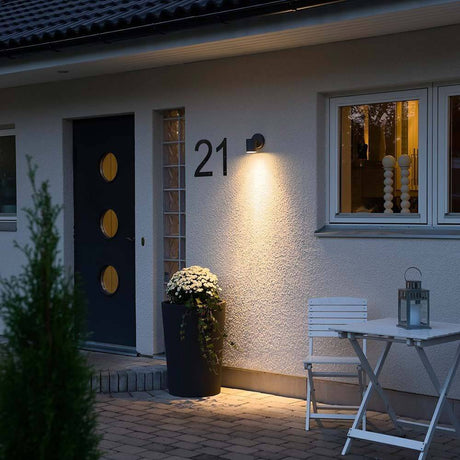 Modena outdoor wall light black, clear glass, reflector illuminates the entrance area of a house.