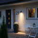 Modena Außen-Wandleuchte Schwarz, klares Glas, Reflektor beleuchtet den Eingangsbereich eines Hauses.