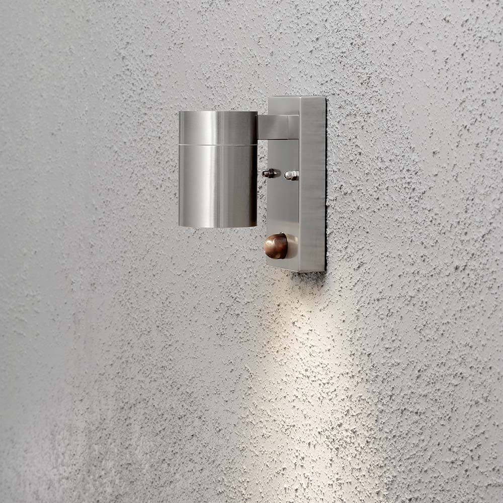 Modena Sensor Außen-Wandleuchte Edelstahl, klares Glas, Reflektor an einer grauen Wand installiert.