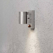 Modena Sensor Außen-Wandleuchte Edelstahl, klares Glas, Reflektor an einer grauen Wand installiert.