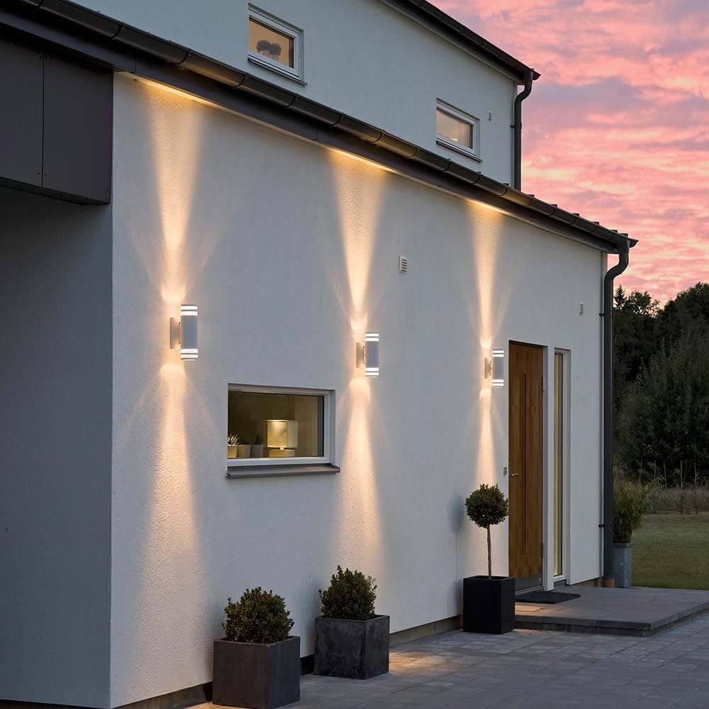 Modena Außen-Wandleuchte mit doppeltem Lichtkegel Weiß, klares Acrylglas, Reflektor an einer modernen Hauswand.