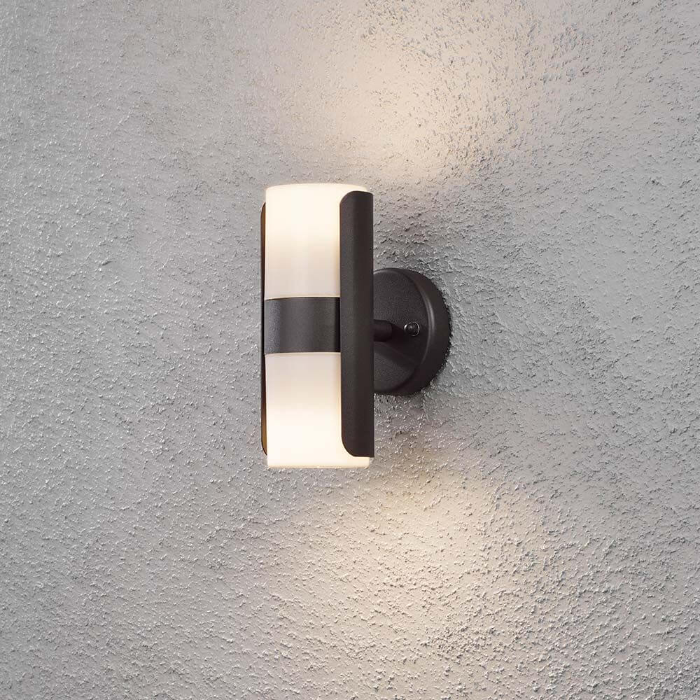 Modena Außen-Wandleuchte mit Lichtkegel Schwarz, opales Acrylglas an einer grauen Wand.