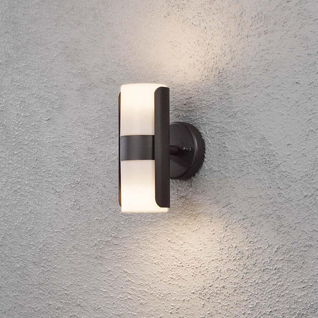 Modena Außen-Wandleuchte mit Lichtkegel Schwarz, opales Acrylglas an einer grauen Wand.