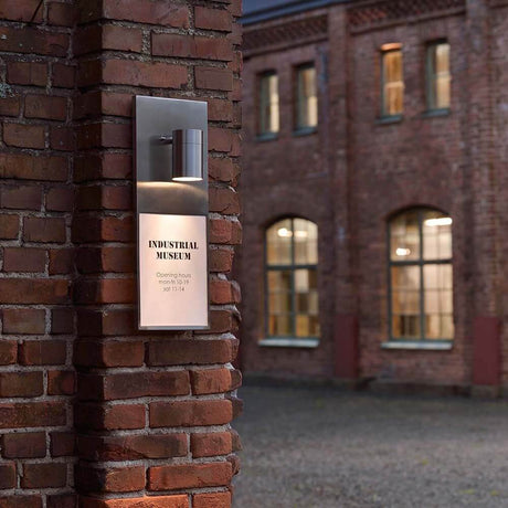 Modena Number DIN A4 lampa numerowa ze stali nierdzewnej na ścianie z cegły, oświetla MUZEUM PRZEMYSŁOWE.