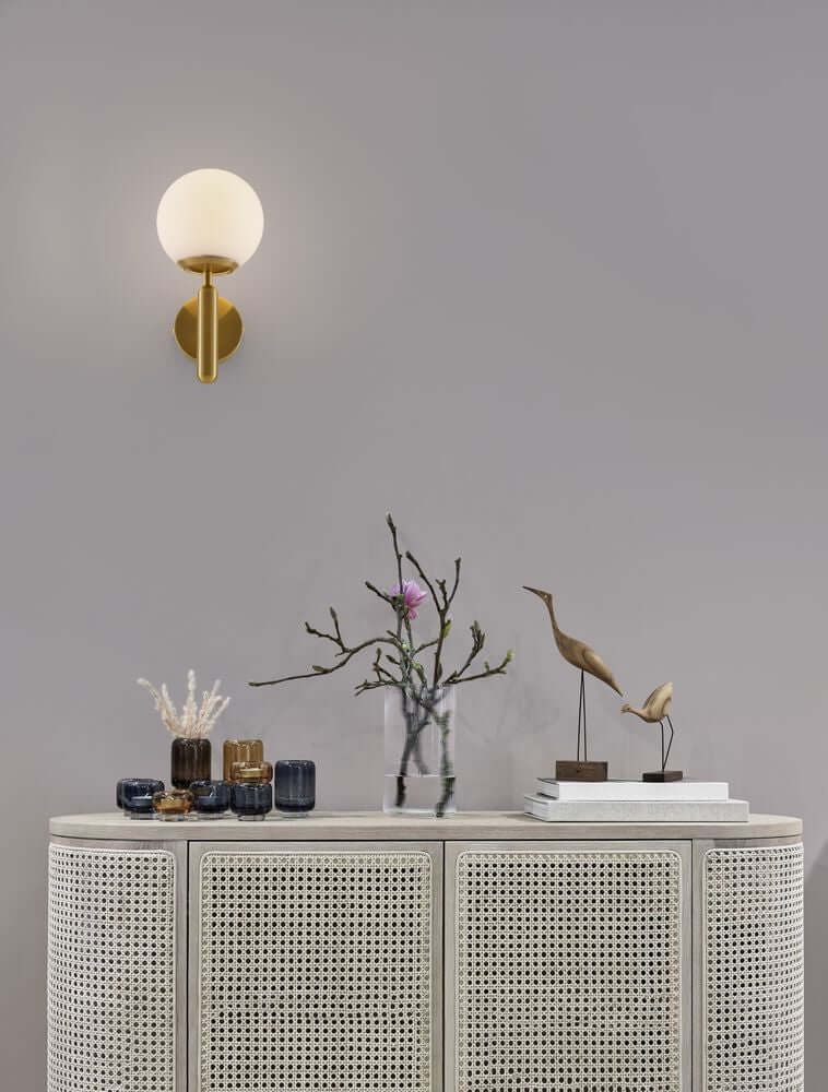 Monet Wandleuchte Gold, Weiß an grauer Wand über Sideboard mit Dekoration, mundgeblasenes opal Glas