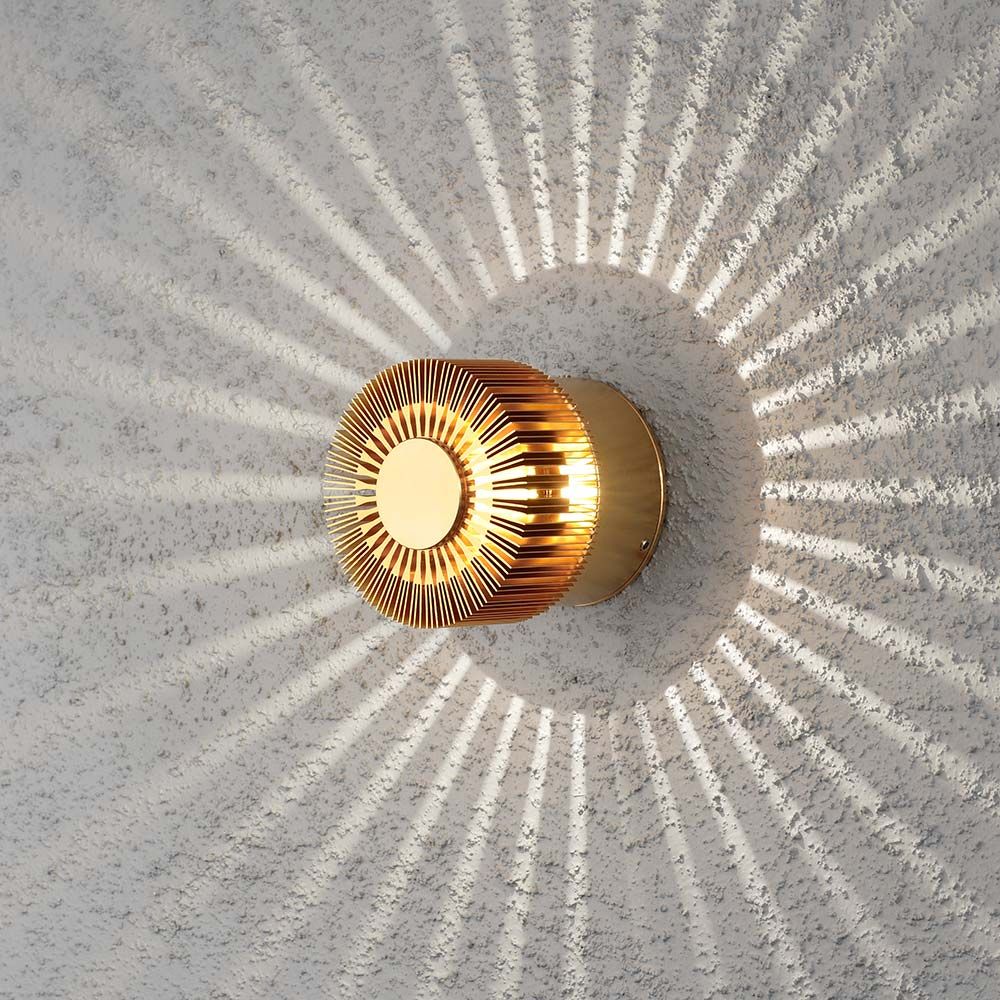Bronzefarbene Monza LED Außen-Wandleuchte mit dekorativem Lichteffekt auf Betonwand.