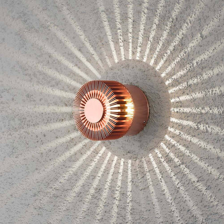 Monza LED effect outdoor wall light in copper color on a wall with a ray pattern.