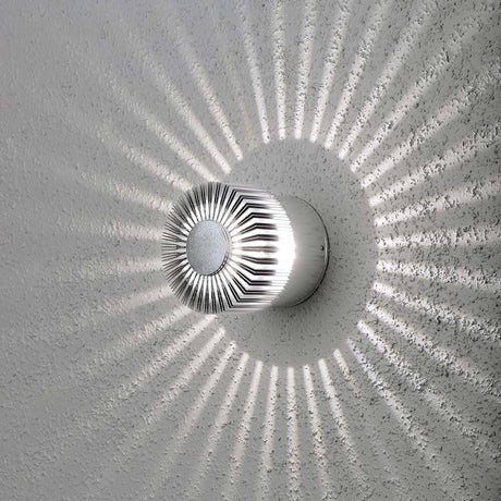 Monza LED applique extérieure à effet avec un design lumineux unique et des effets d’ombre élégants sur le mur.