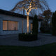 Monza LED Erdspießleuchten Set 2-tlg. 12V beleuchtet einen Gartenbereich in der Dämmerung.
