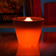 Rotaliana Multipot+ Tischleuchte Kabelcontainer + Ladestation Chrom in leuchtendem Orange auf Tisch.