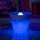 Rotaliana Multipot+ Tischleuchte Kabelcontainer + Ladestation Chrom in blau beleuchtet auf einem Tisch.
