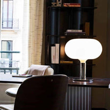 Lampe de table classique Nemo Am1N de 1969 chromée sur une table dans un intérieur moderne.