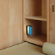 Nemo Applique Cylindrique Petite Wandlampe 16cm in hellblauem Metall, montiert an einer Holzregalwand.