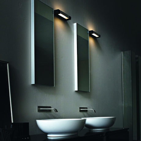 Nemo Ara 29 LED Wandleuchte in modernem Badezimmer mit zwei Spiegeln und Waschbecken.