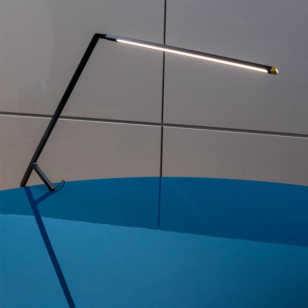 Nemo Bird LED table lamp with gesture control on a blue table, elegant design and modern functionality.