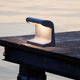 Nemo Borne Béton Petite Outdoor LED Tischlampe IP44 auf einem Holztisch am Wasser bei Sonnenuntergang.