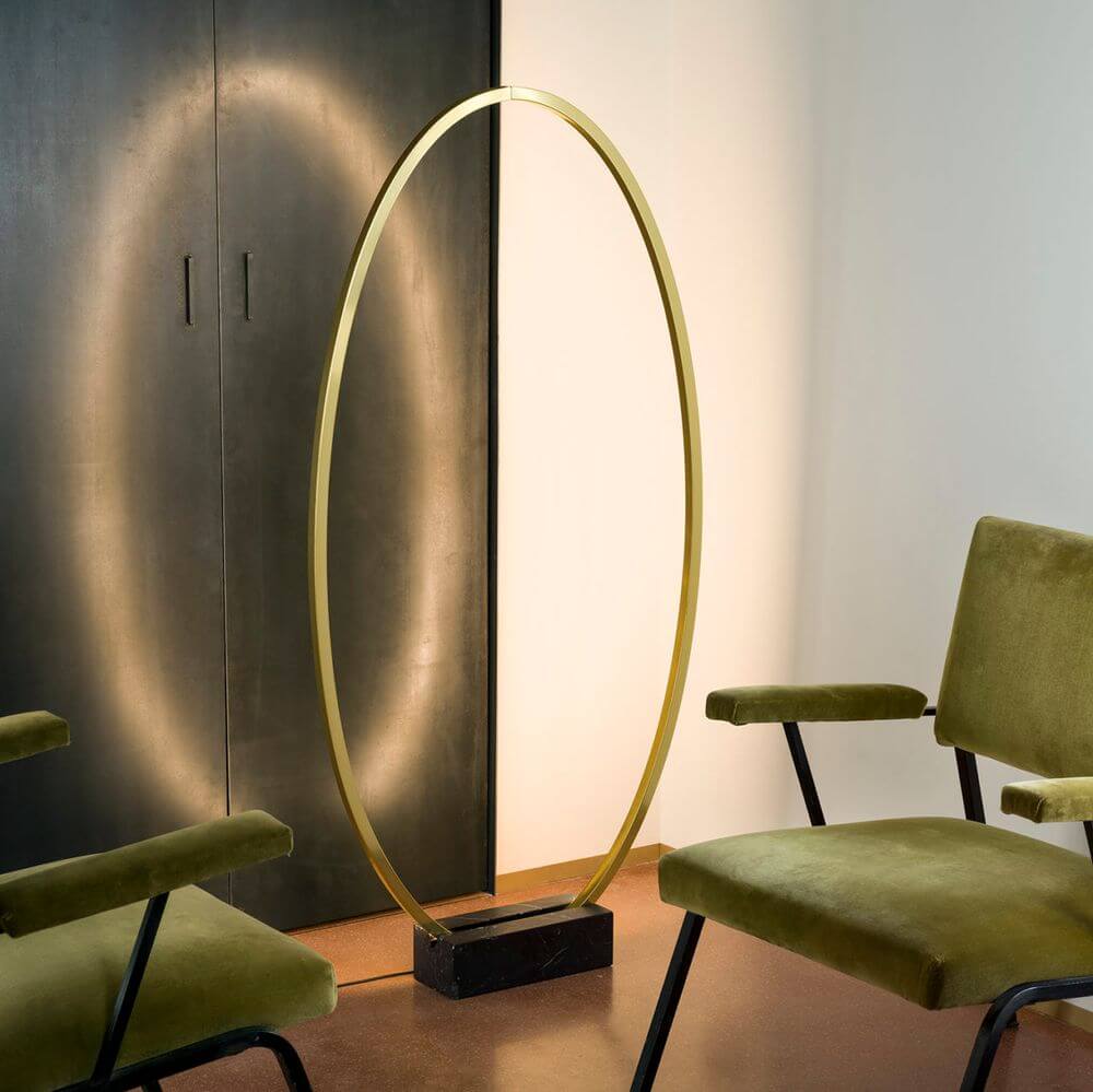 Elegante Stehleuchte Ellisse mit schwarzem Marmorfuss und goldener Ringleuchte in modernem Raumdesign.