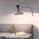 Nemo Lampe De Marseille Mini Wandleuchte mit Arm über einem grauen Sofa, stilvolle Beleuchtung im Raum.