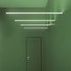 Moderne Wandleuchte in einem grünen Flur mit vier schmalen LED-Leisten, die direkt und indirekt beleuchten.