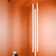 Nemo Linescapes Vertical LED Hängelampe 115cm in einem modernen Interieur mit oranger Wandfarbe.