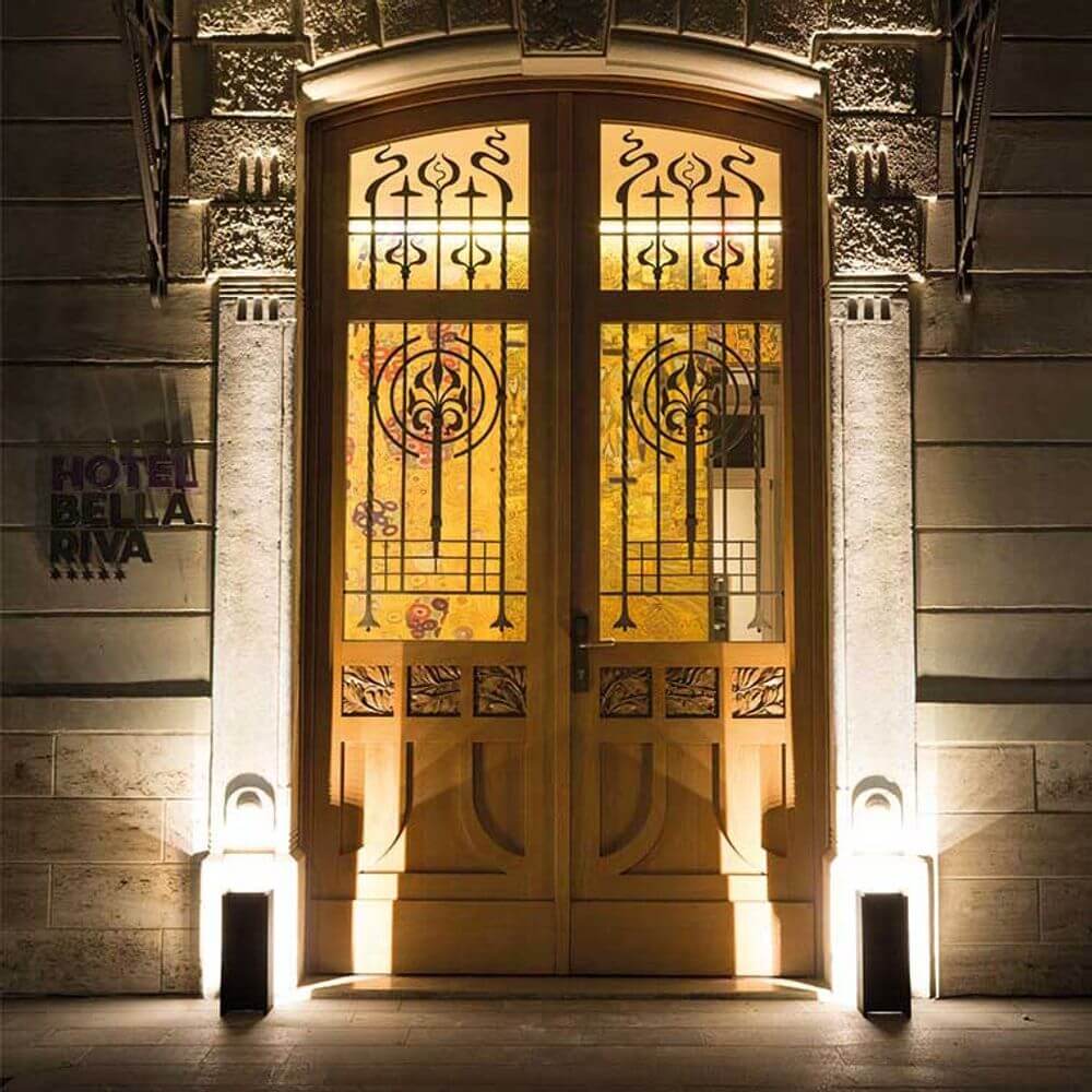 Eingangstür des Hotels Bella Riva, beleuchtet mit Nemo Mais Plus Que Cela Je Ne Peux Pas LED Pollerleuchte IP65.