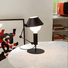 Nemo Mr. Light table lamp on a table, with an adjustable arm and matt black metal for diffuse light.