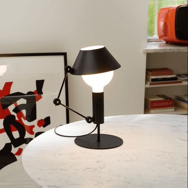 Nemo Mr. Light table lamp on a table, with an adjustable arm and matt black metal for diffuse light.