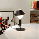 Nemo Mr. Light Tischlampe auf einem Tisch, mit beweglichem Arm und matt schwarzem Metall für diffuses Licht.