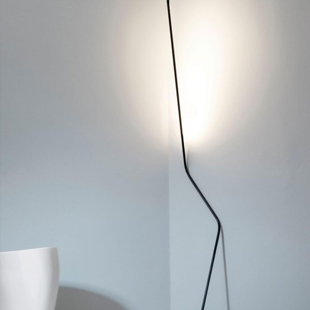 Nemo Neo LED Stehlampe, an die Wand gelehnt, aus gebogenem Stahl und mattschwarzem Aluminium, mit indirekter Beleuchtung.