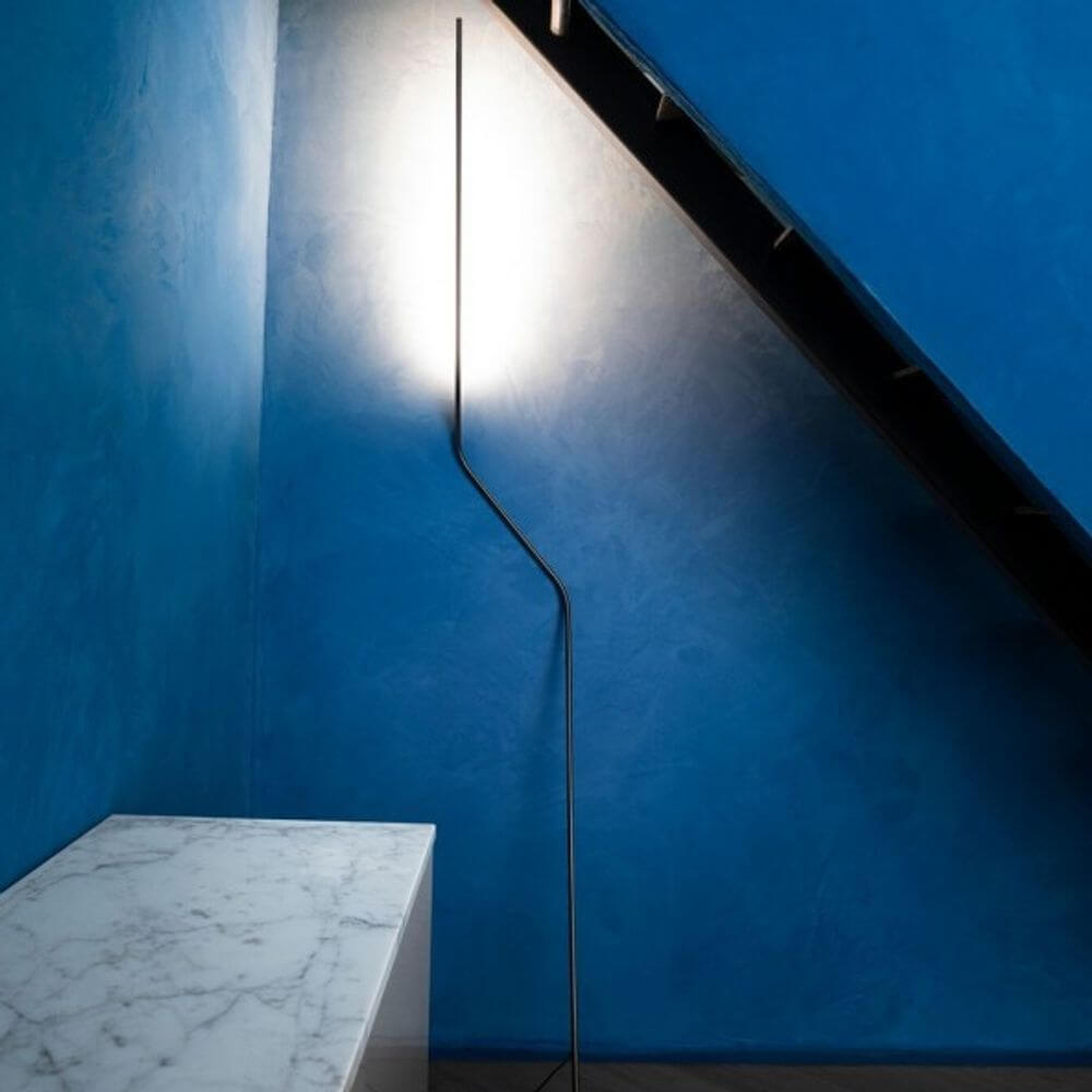 Nemo Neo LED Stehlampe in modernem Design mit indirekter Beleuchtung an blauer Wand.