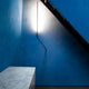 Nemo Neo LED Stehlampe zum anlehnen in einem modernen Raum mit blauer Wand