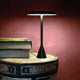 Nemo Panama LED Tischlampe 45cm auf einem Tisch neben Büchern, stilvolles Design mit mattschwarzer Oberfläche.