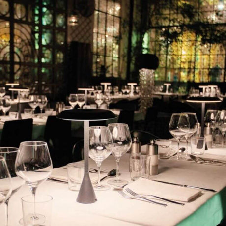 Nemo Panama Mini LED Akku-Tischlampe 30cm auf eleganter Restaurant-Tischdekoration bei gedämpftem Licht.