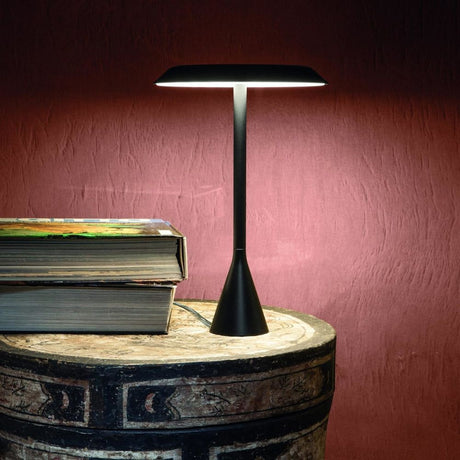 Nemo Panama Mini LED Tischleuchte 30cm in Schwarz auf einem Tisch mit Büchern im Hintergrund.