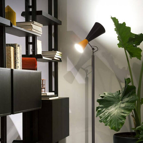 Lampadaire Nemo Parliament indirect/direct dans un espace moderne avec bibliothèque et plante.